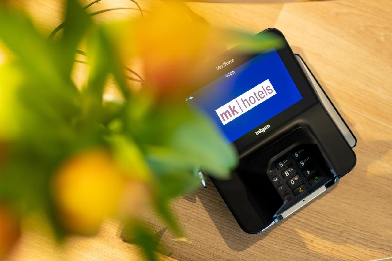 Mk Hotel Tirana Ринас Экстерьер фото A mobile phone with the MK1Hotels logo on the screen